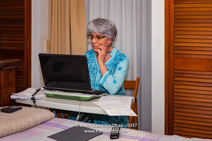 Senior Hispanic Lady With Silver Hair, Working From Home On Her Computer