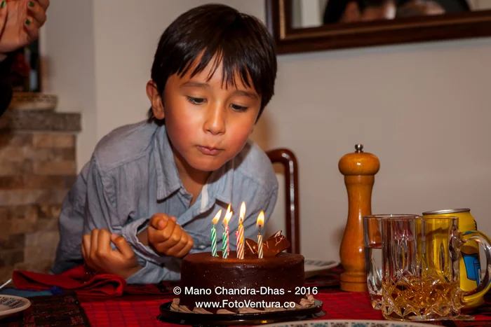A boy blowing out the candles on his birthday cake