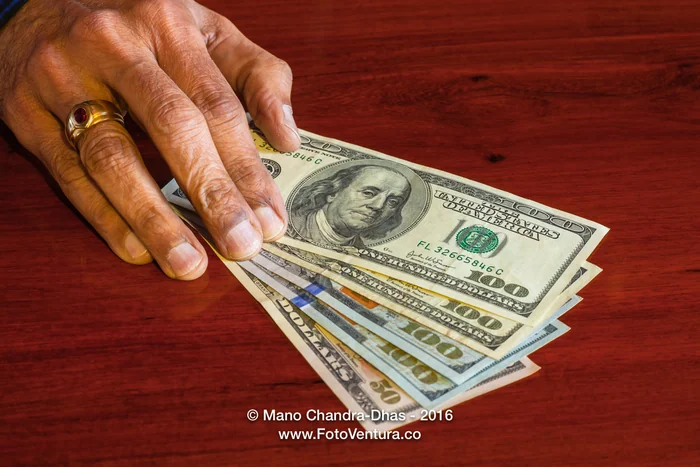 Dollars, USA currency - Pushing the Money on Rosewood Table