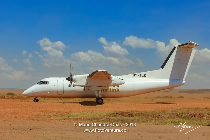 Masai Mara, Kenya - A Safarilink Turboprop Airplane Has Just Landed On The Olkiombo Dirt Airstrip On The Great Rift Valley: It Has Not As Yet Come To A Complete Stop. A Clear Blue Sky Completes The Picture