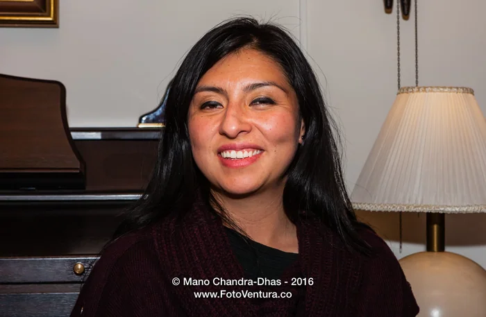 Portrait of a smiling woman beside a piano