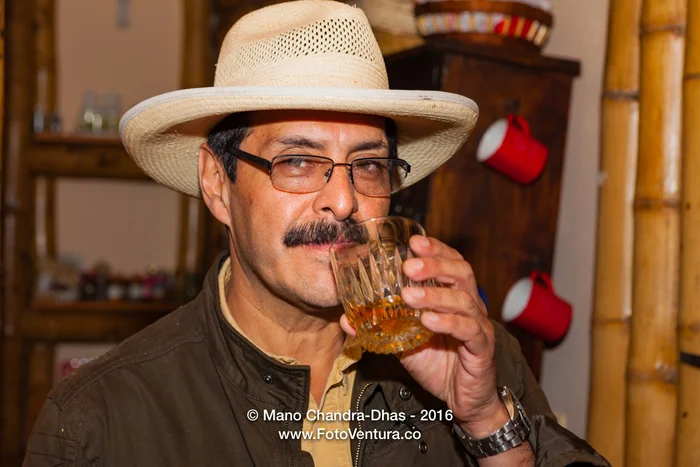 Portrait of a man in a straw hat sipping a drink