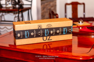 A Safely Courier Delivered Amazon Cardboard Package, Sealed With Amazon Prime Adhesive Tape, Placed On A Highly Polished Rosewood Table