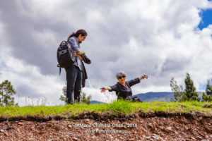 Latin Lady With Silver Hair Expresses Joy In The Beauty Of Nature In the Tranquil Surroundings The Andes Mountains Near The Town Of Villa de Leyva In The Colombia Department Of Boyacá While Her Son Looks On In Amusement