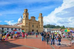 Chiquinquirá, Colombia: It is Sunday afternoon on the Plaza Mayor in the Andes town of Chiquinquirá in the Department of Boyacá, in the South American Country of Colombia. Many local residents and Colombian tourists are seen enjoying the ambience of the town square. Vendors sell toys and snacks to visitors. In the background is the 19th Century Basilica of Our Lady of the Rosary. It houses the famous painting of Our Lady of The Rosary, also referred to as the Virgin of Chiquinquirá, the Patron Saint of Colombia. It is designed in the Neo-classical style of architecture and is a destination of Catholic pilgrimage in South America. The altitude at street level is about 8400 feet above mean sea level. Photo shot in the late afternoon sunlight; horizontal format.