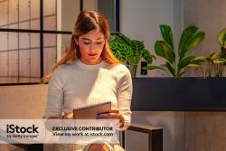 An Office Worker Engrossed In Her Digital Tablet While She Waits